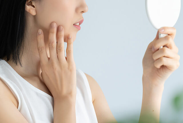顔を鏡で見ている女性
